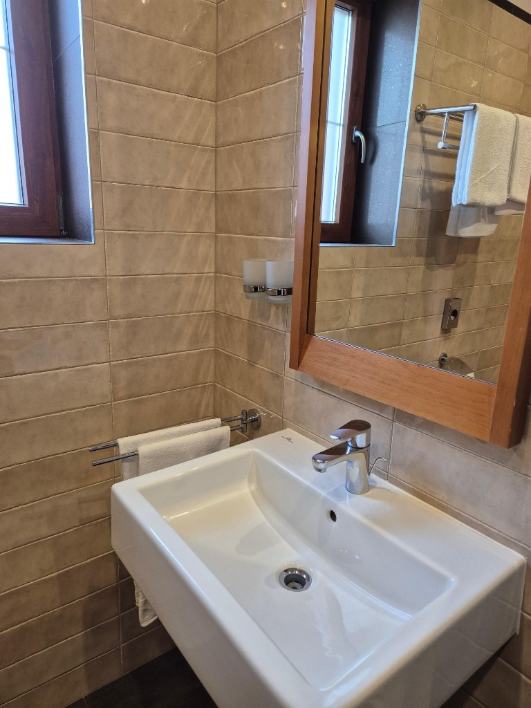 Glänzendes Hotel-Waschbecken mit Chromarmatur und frischen Handtüchern