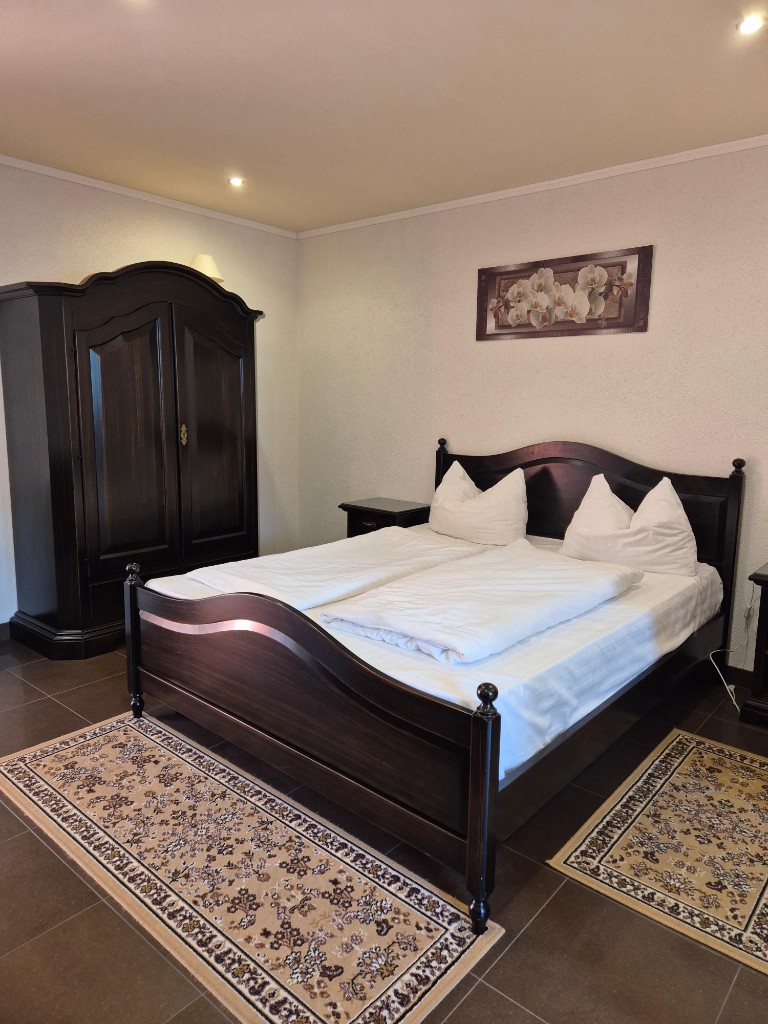 Komplett hergerichtetes Hotelzimmer mit weißer Bettwäsche und dunklem Schrank